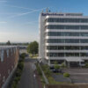 Titelbild der Kundenreferenz "Re-Organisation der IT " beim ORBIT-Kunden Reifenhäuser. Hochhaus, die Firmenzentrale, mit Straße vor blauem Himmel.